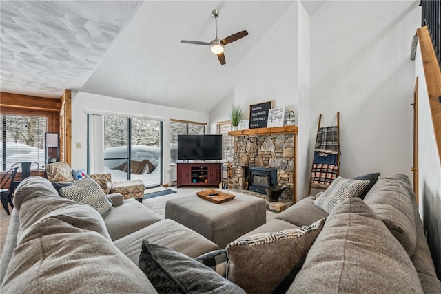 living room with ceiling fan, a wood stove, plenty of natural light, and high vaulted ceiling