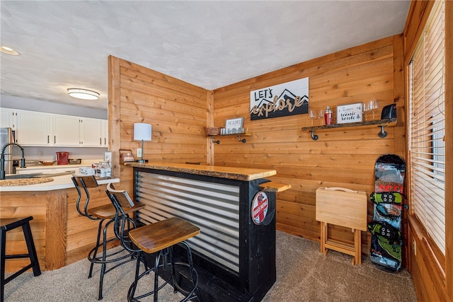 bar featuring dark colored carpet, white cabinets, and wooden walls