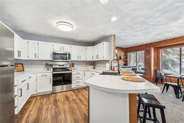 kitchen with kitchen peninsula, appliances with stainless steel finishes, sink, and a breakfast bar area