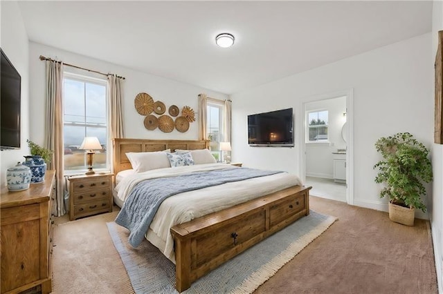 bedroom with light colored carpet, connected bathroom, and multiple windows