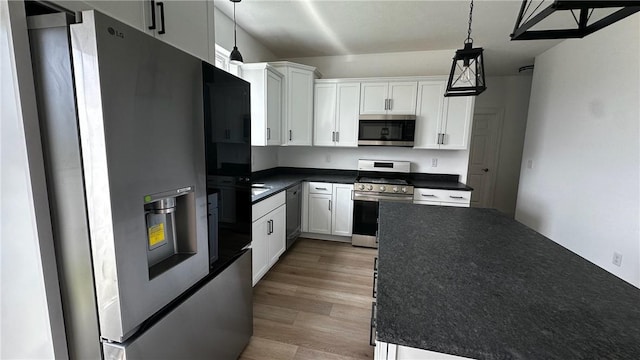 491 Shannon Dr, Mount Pleasant Twp Wml, PA 15666 - kitchen featuring appliances with stainless steel finishes, dark countertops, light wood-type flooring, white cabinetry, and hanging light fixtures