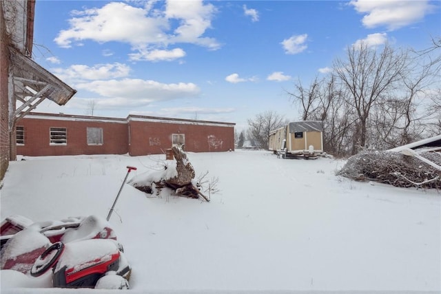 snowy yard featuring a storage shed