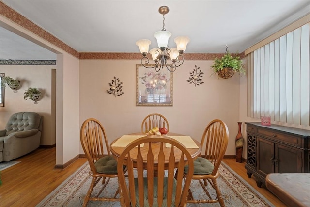 dining space with light wood-type flooring and a notable chandelier