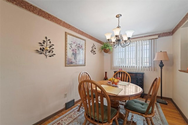 dining space with crown molding, a chandelier, and hardwood / wood-style flooring