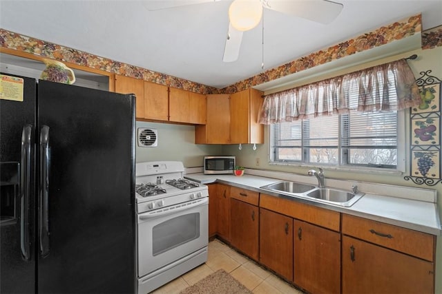 kitchen featuring ceiling fan, black refrigerator with ice dispenser, white range with gas cooktop, light tile patterned flooring, and sink