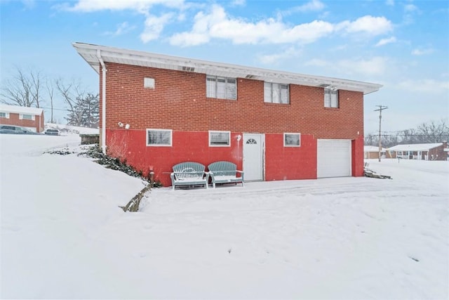 snow covered back of property with a garage