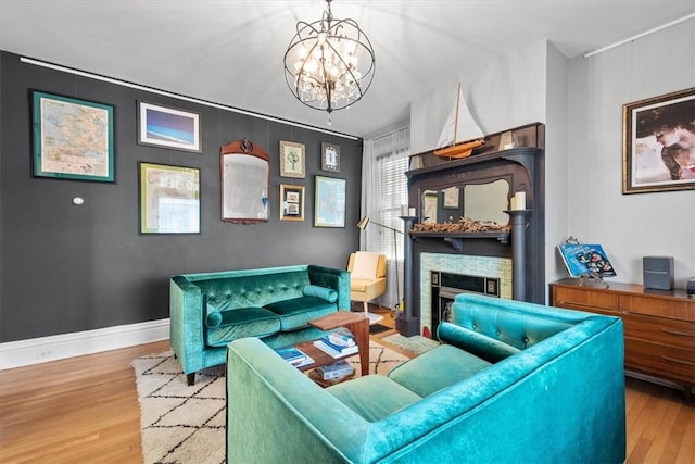 living room featuring wood-type flooring, a notable chandelier, and a fireplace