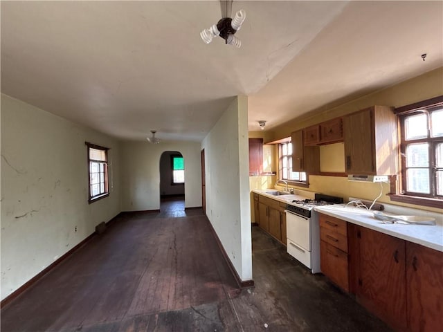 kitchen featuring dark wood-type flooring, white range with gas stovetop, and sink