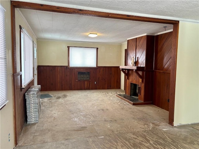 unfurnished living room featuring a wealth of natural light, heating unit, and ornamental molding