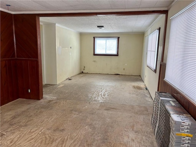 spare room with crown molding and wood walls