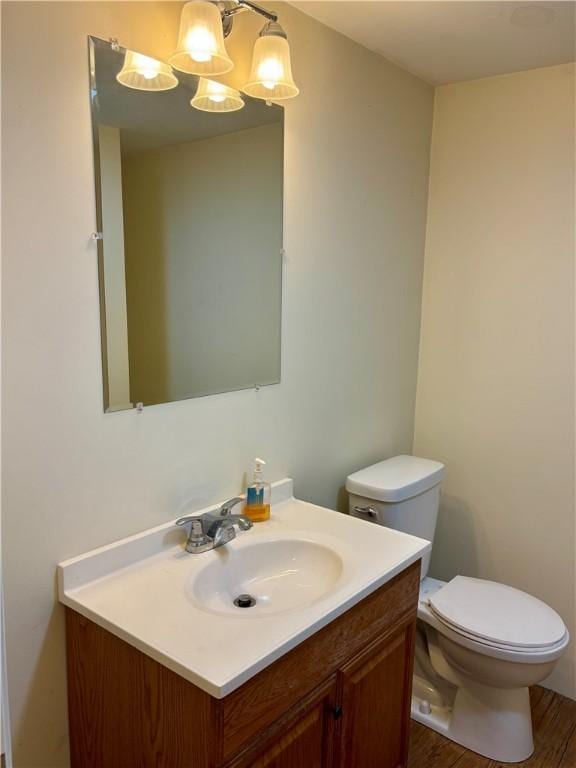 bathroom with toilet, an inviting chandelier, wood-type flooring, and vanity