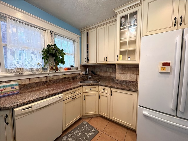 kitchen with sink, white appliances, a textured ceiling, light tile patterned floors, and cream cabinetry