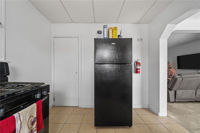 kitchen featuring light tile patterned flooring, a drop ceiling, and black appliances