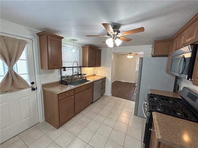 kitchen featuring light tile patterned floors, stainless steel appliances, ceiling fan, and sink