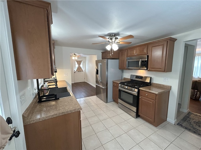 kitchen with ceiling fan, sink, stainless steel appliances, and light tile patterned flooring