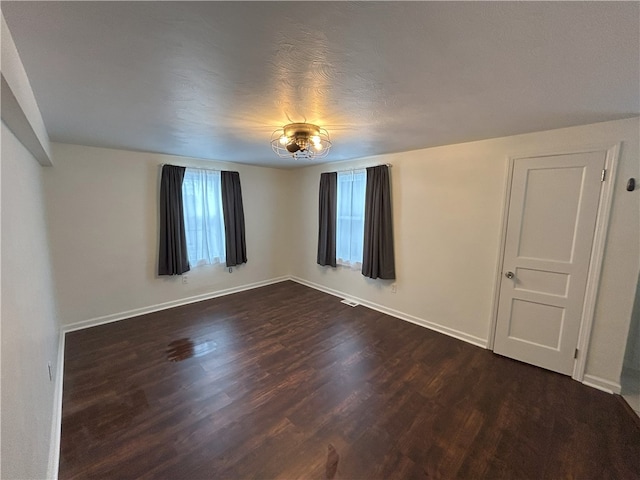 empty room with dark wood-type flooring and a textured ceiling