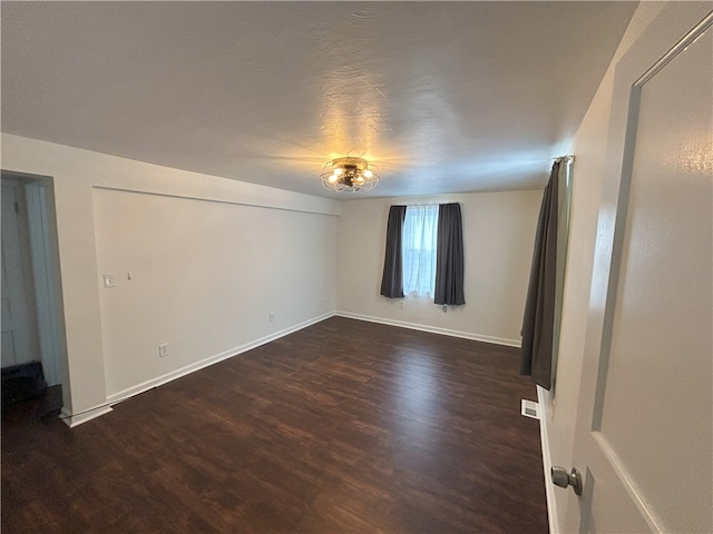 empty room featuring a textured ceiling and dark wood-type flooring