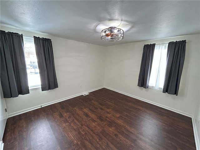 unfurnished room with a textured ceiling and dark wood-type flooring