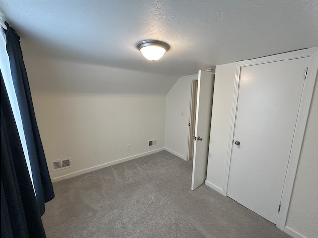 bonus room featuring a textured ceiling, light carpet, and vaulted ceiling