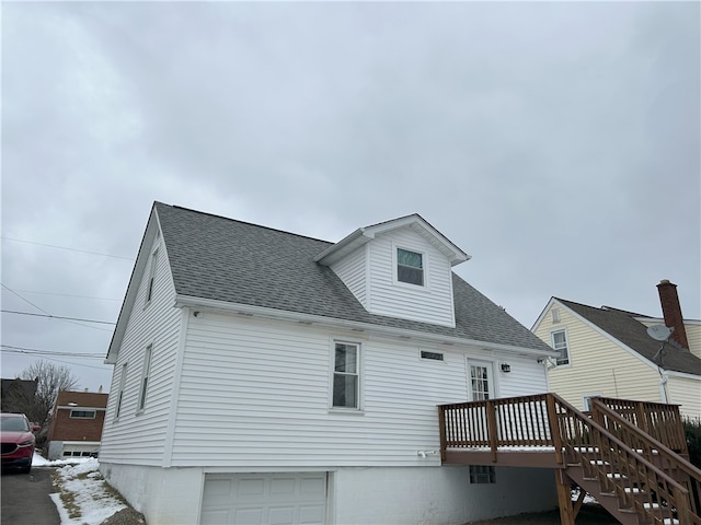 rear view of house featuring a garage and a wooden deck