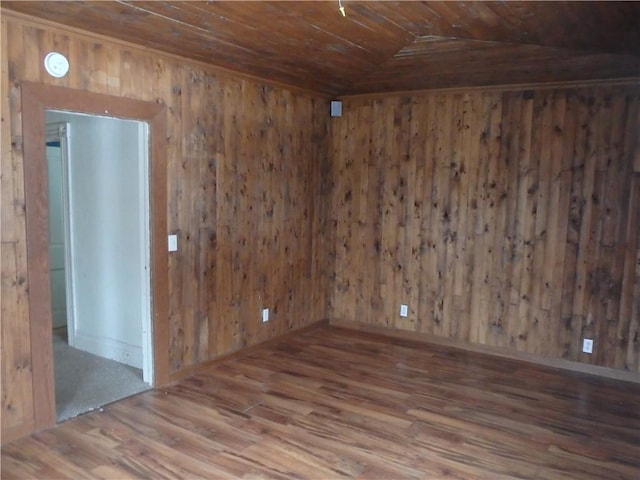 spare room featuring wooden ceiling, wood-type flooring, lofted ceiling, and wooden walls