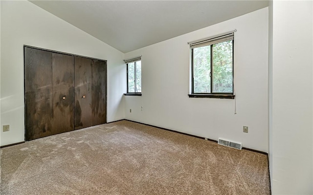 unfurnished bedroom with vaulted ceiling, a closet, and carpet