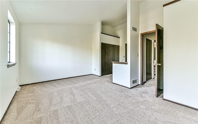 spare room featuring vaulted ceiling and light colored carpet