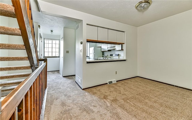 kitchen featuring light colored carpet, a textured ceiling, white cabinets, and white fridge