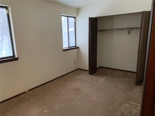 unfurnished bedroom featuring light colored carpet and a closet