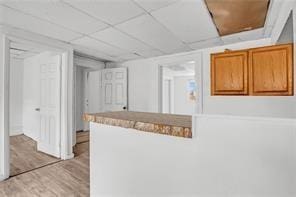 kitchen featuring light wood-type flooring and a drop ceiling