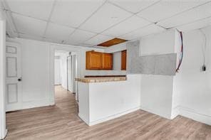 interior space featuring a paneled ceiling and light hardwood / wood-style flooring