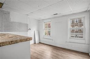 interior space with hardwood / wood-style flooring and a drop ceiling