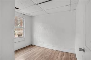 spare room with a drop ceiling and hardwood / wood-style flooring