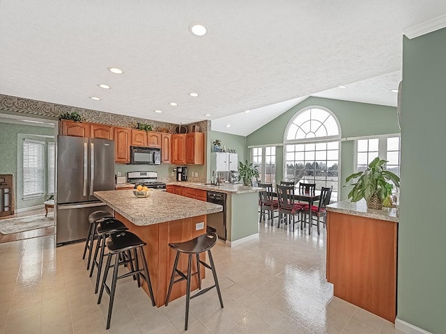 kitchen featuring a textured ceiling, black appliances, a center island, kitchen peninsula, and a breakfast bar area