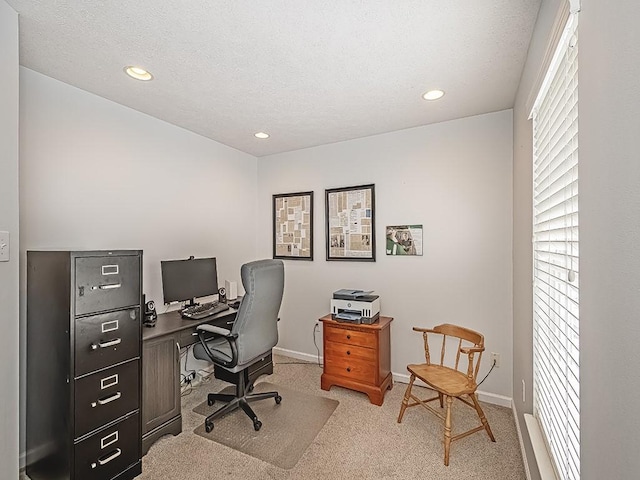 office space featuring a textured ceiling, a healthy amount of sunlight, and light colored carpet