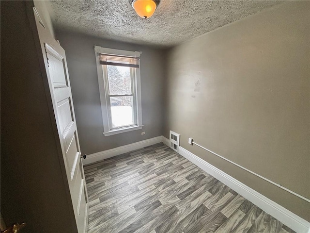 empty room featuring wood-type flooring and a textured ceiling