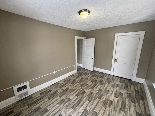 spare room with a textured ceiling and dark wood-type flooring