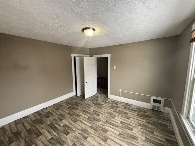 spare room featuring dark hardwood / wood-style floors and a textured ceiling