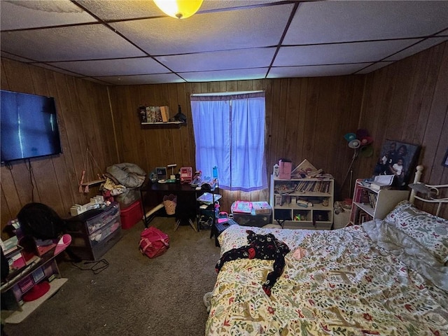 carpeted bedroom with a paneled ceiling and wooden walls