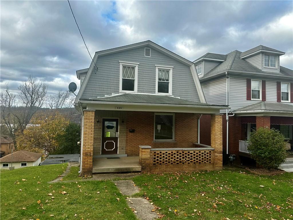 front facade featuring covered porch and a front yard