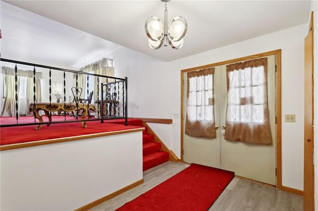 doorway featuring light wood-type flooring and an inviting chandelier