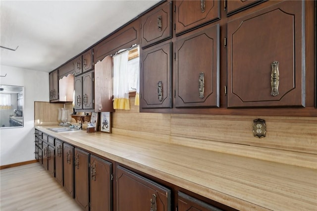 kitchen with sink, butcher block countertops, and dark brown cabinets