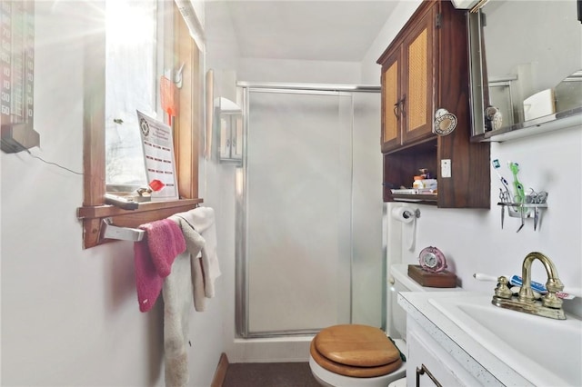 bathroom with a shower with shower door, toilet, and vanity