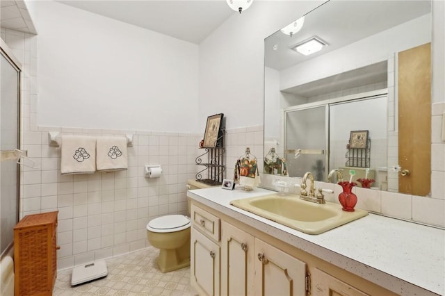 bathroom featuring toilet, vanity, tile patterned flooring, tile walls, and a shower with door