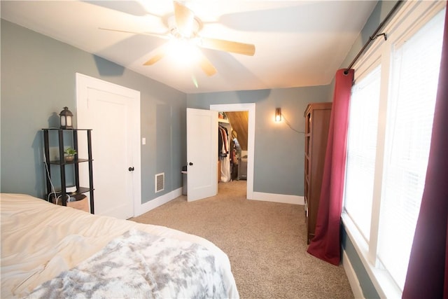 bedroom featuring ceiling fan, light colored carpet, a closet, and a spacious closet