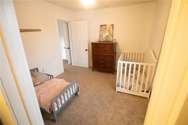 carpeted bedroom featuring a nursery area