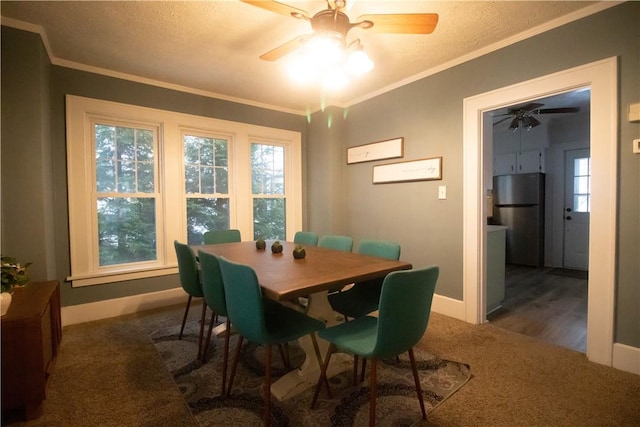 carpeted dining space featuring ceiling fan, ornamental molding, and a healthy amount of sunlight