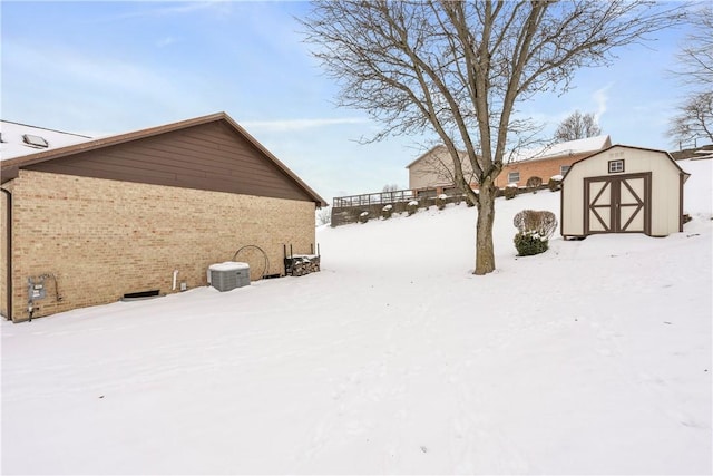 snowy yard with a shed and central AC unit