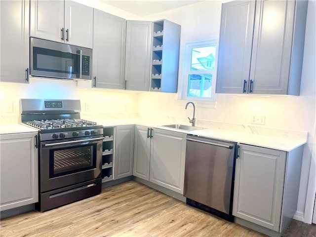 kitchen with light hardwood / wood-style floors, sink, appliances with stainless steel finishes, and gray cabinets