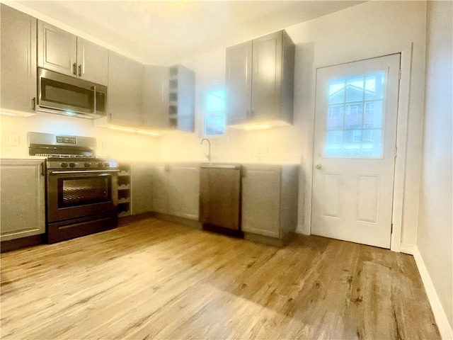 kitchen featuring a wealth of natural light, stainless steel appliances, light hardwood / wood-style flooring, and gray cabinets